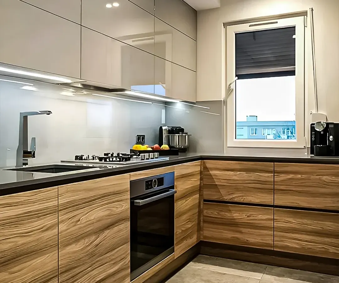 This L-shaped modular kitchen features a dual-tone design with high-gloss grey upper cabinets and warm wood-grain lower units. We've integrated under-cabinet LED lighting for task illumination and built-in appliances for a seamless, modern look.