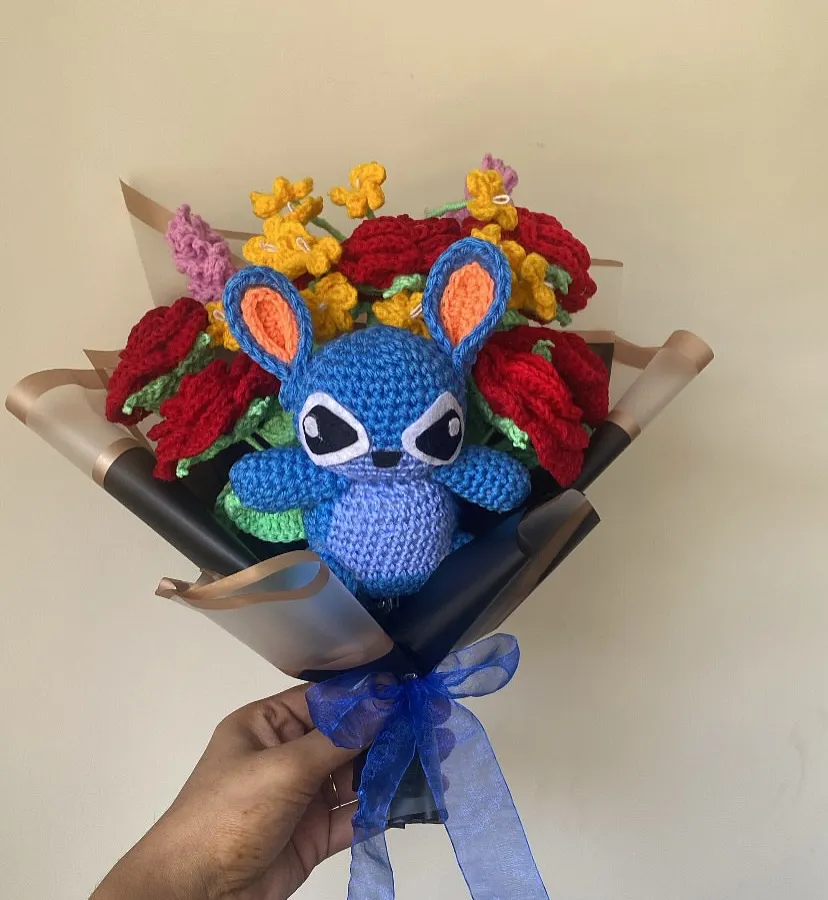 For the fans of 'Ohana'! I had so much fun making this custom Stitch bouquet. The little blue character is nestled among vibrant red and yellow crochet flowers, all wrapped in stylish black and gold paper. It’s a perfect example of how we can bring your favorite characters to life.