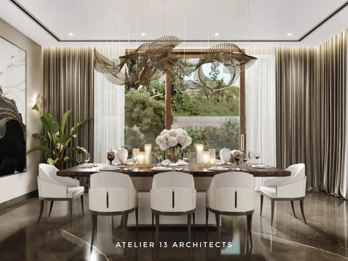 In this farmhouse dining room, a fluidic Italian metal and glass chandelier hangs above a veneer-top table with a fluted leather base. We used bronze Armani marble for the flooring and surrounded the space with beige Italian chairs to create a warm, opulent setting for gatherings.