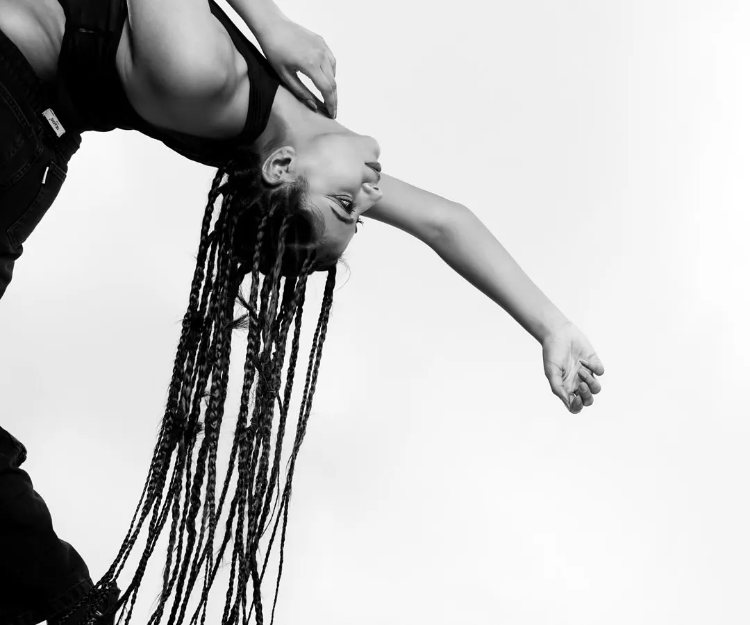 An artistic black and white photograph capturing a model in a dramatic backbend, with long braids cascading towards the floor. This highlights my creative approach to editorial photography and mastery of high-contrast monochrome lighting.