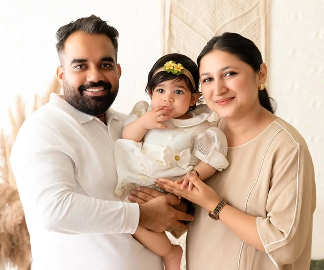 A happy family portrait featuring a mother, father, and their baby, captured in a bright, naturally lit setting with a boho-chic theme. I aim to capture genuine connection and joy in my family sessions.