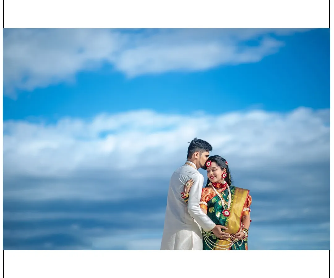 A stunning maternity portrait celebrating Maharashtrian heritage. The vibrant Nauvari saree and traditional jewelry look incredible against the dramatic sky, creating a timeless memory for the expecting couple.