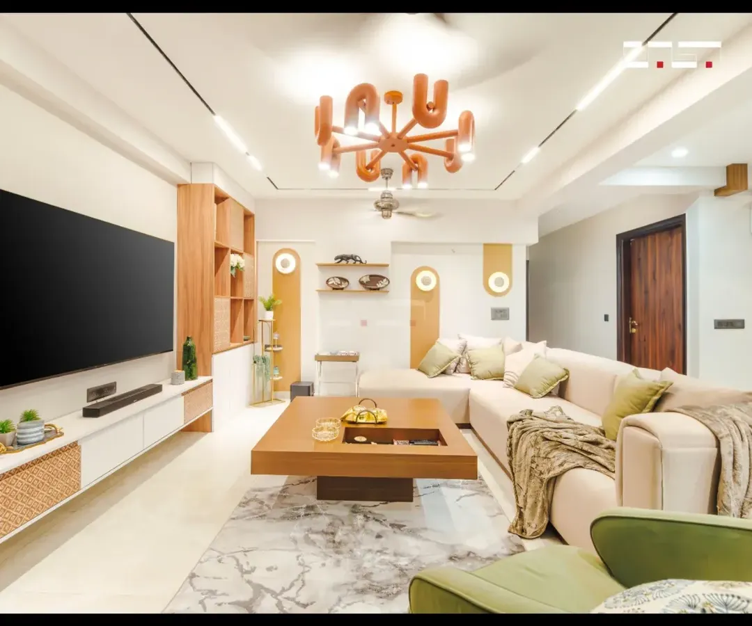 I designed this living room in a Jaipur apartment to be a harmonious blend of form, function, and comfort. The space features an L-shaped sofa, a statement chandelier, and custom wooden cabinetry with rattan details, all unified by a warm, earthy color palette.