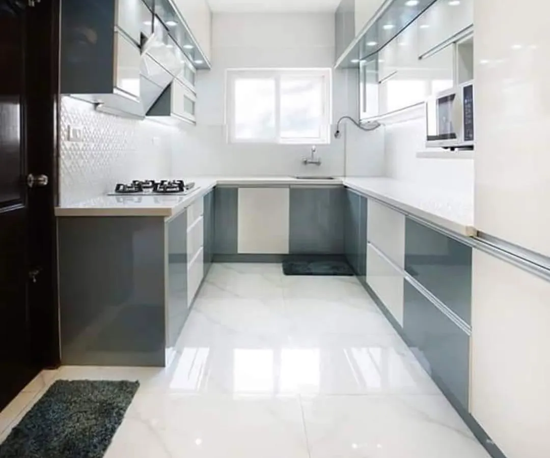 Here is a finished U-shaped modular kitchen, designed for maximum efficiency. The white and grey handleless cabinets create a clean, modern look, while under-cabinet lighting ensures the workspace is always well-lit.