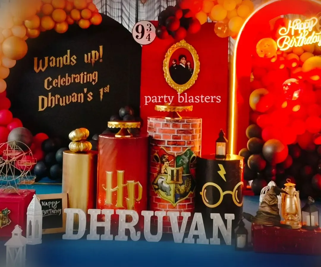 Wands up for a magical Harry Potter first birthday. This detailed setup features iconic elements like the Platform 9 3/4 sign, a Sorting Hat, themed pedestals, and a custom "Wands up!" backdrop, all in the classic Gryffindor colors.