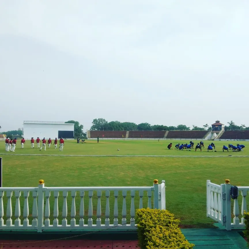A wide view of the teams on the field during a competitive match. Our academy ensures players get the full experience of playing in large, well-maintained stadiums, preparing them for the pressures of professional cricket.