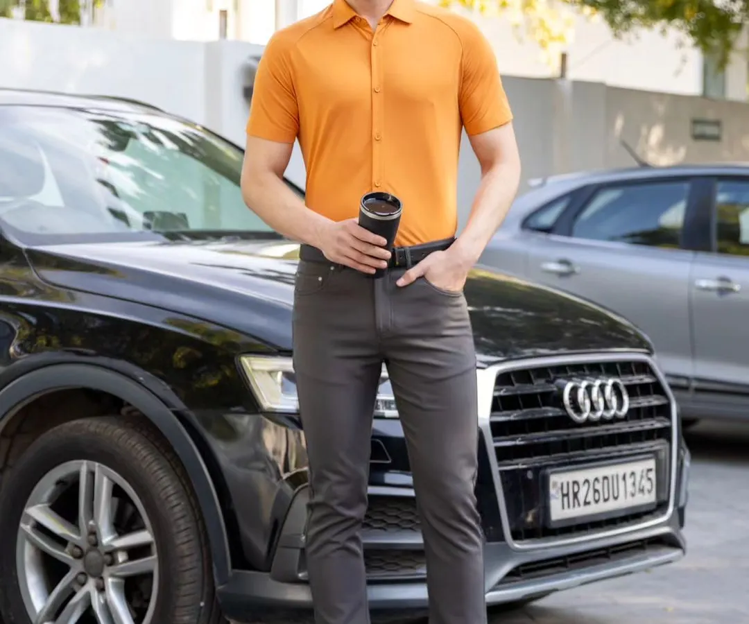 A male model wearing a short-sleeved apricot shirt and dark trousers, captured in a sharp, outdoor lifestyle shot for a commercial brand. This demonstrates my clean and professional e-commerce photography style, perfect for apparel catalogs.