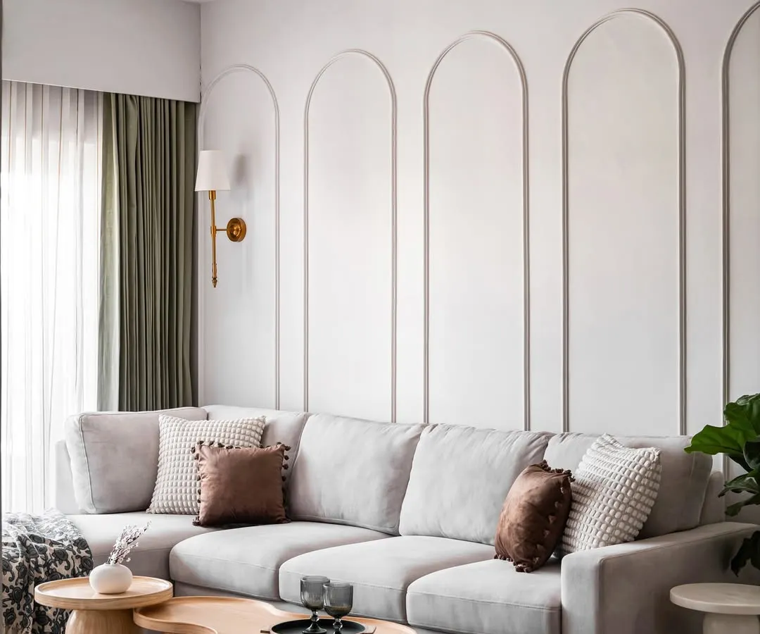 We designed this luxurious living room with a focus on creating a serene and sophisticated atmosphere. The large, comfortable L-shaped sofa is perfect for family time, and the wall is adorned with elegant arched mouldings. The organic-shaped wooden coffee tables and a striped rug add texture and warmth to the space.
