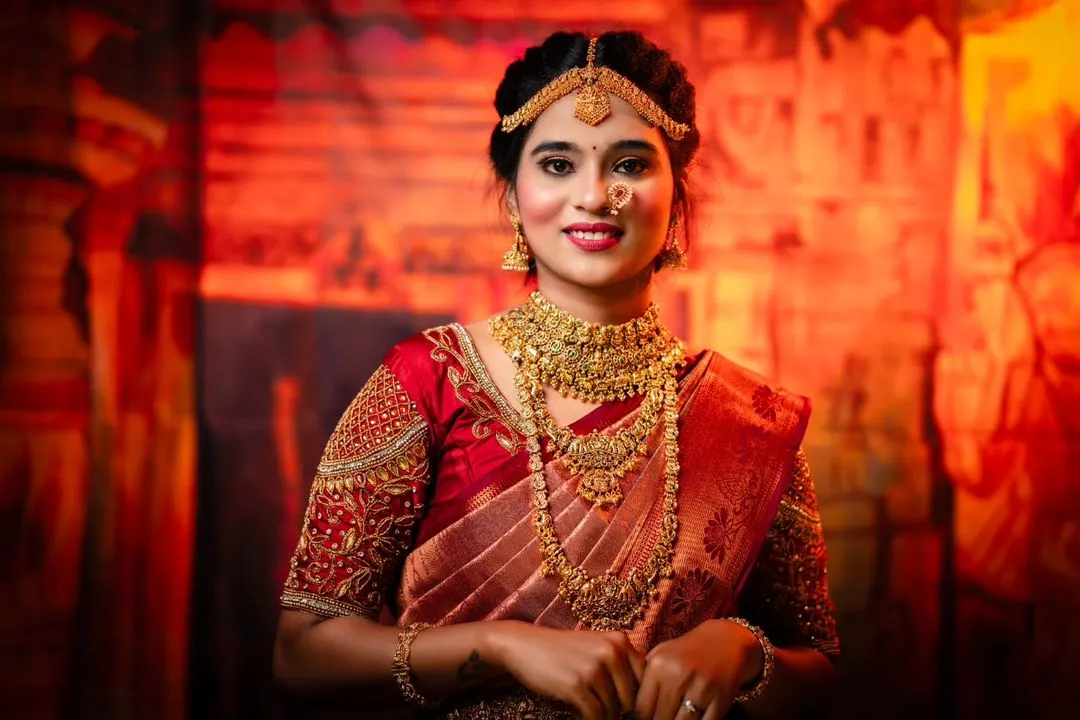 Feel like a queen on your special day with our classic red bridal pattu saree. This rental comes with a heavily embroidered aari work blouse and is paired with a full temple jewellery set, also available for rent.