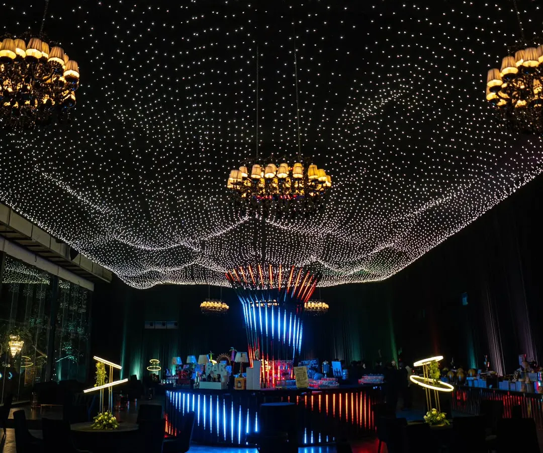 We transformed an indoor venue into a celestial wonderland with a custom starlit ceiling. This immersive lighting installation, combined with elegant chandeliers, creates a magical atmosphere perfect for gala dinners and milestone celebrations.