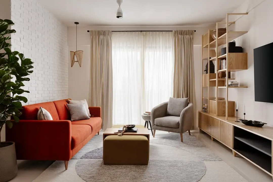 This living room is the essence of a soulful sanctuary. I used a burnt orange sofa for a pop of warmth against a neutral backdrop, complemented by a custom wooden TV unit with open shelving. The design balances comfort and style, creating a space that is both beautiful and practical for everyday life.