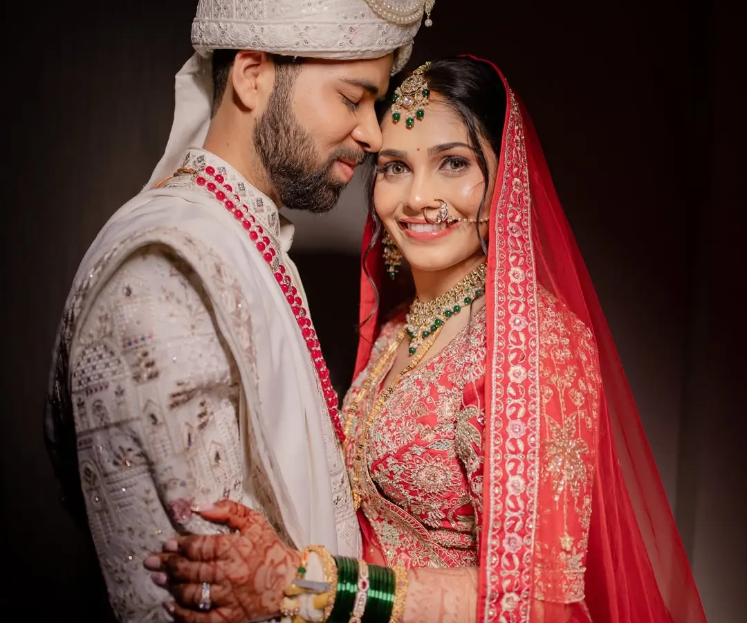 A perfect portrait of the happy couple. My goal is to ensure both the bride and groom look and feel their absolute best, creating timeless memories like this one. This look features classic red lehenga styling with coordinated groom makeup.