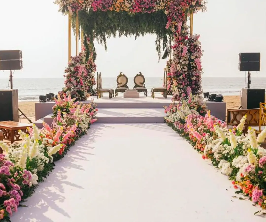 Imagine saying 'I do' with the ocean as your witness. I design breathtaking beachside ceremonies, like this one in Goa, complete with a lush floral mandap and an elegant aisle, ensuring your seaside wedding is as serene and beautiful as the setting itself.