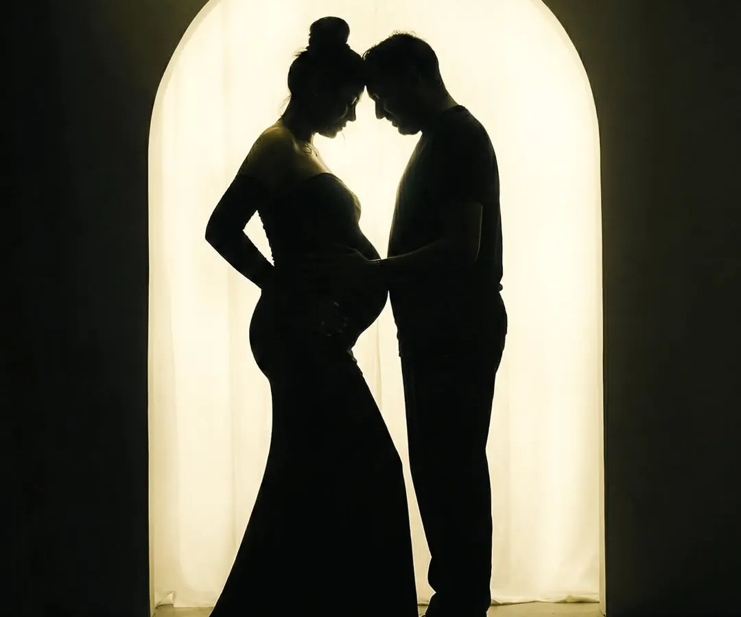 There is a special magic in silhouette portraits. This image focuses purely on the connection between the expecting parents, their shapes telling a story of love and anticipation against a warm, glowing archway in my studio.