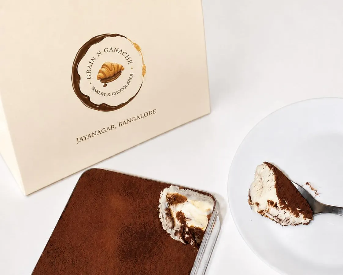 Tiramisu is ready in our takeaway box, with cocoa on top and a spoonful showing the coffee-soaked layers.