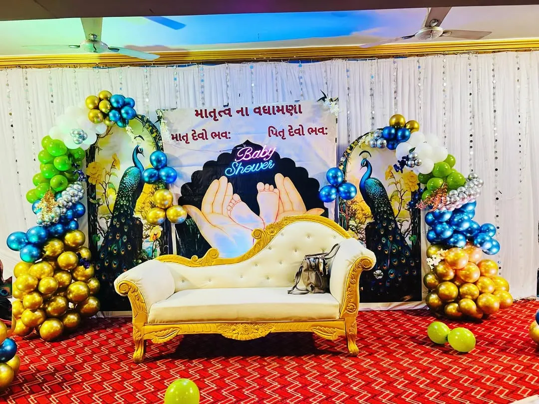 We create beautiful and culturally rich setups for baby showers. This stage features traditional peacock motifs, elegant seating for the mother to be, and a custom backdrop with blessings written in Gujarati, all framed by vibrant balloon arrangements.