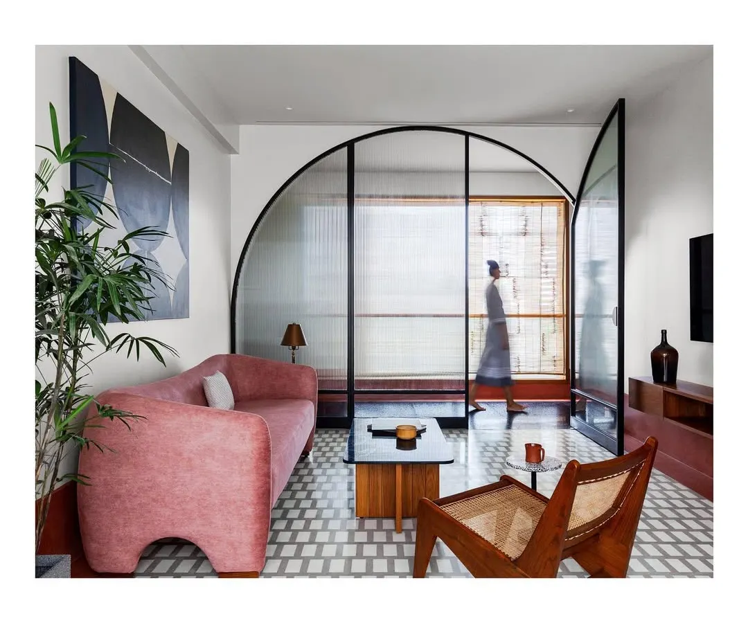 In this lounge, I used a bold color palette and a custom arched glass screen to define the space while maintaining a sense of openness. The design balances modern art with classic materials for a home that feels both exciting and comfortable.