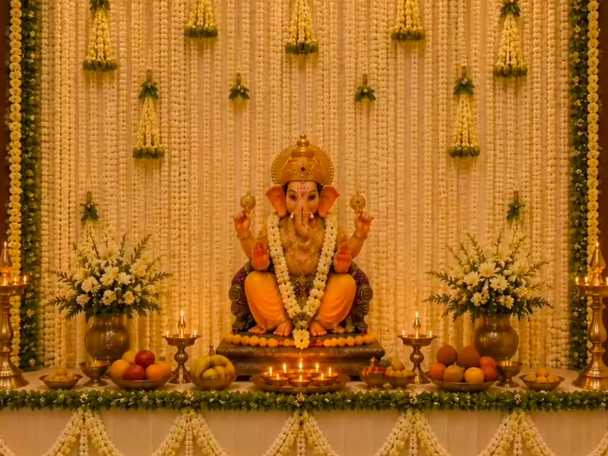 For a Ganapathi puja, I created this intricate backdrop using strings of white jasmine flowers (malli poo) and green leaf borders. The setup includes traditional brass lamps (diyas) and floral arrangements flanking the deity.