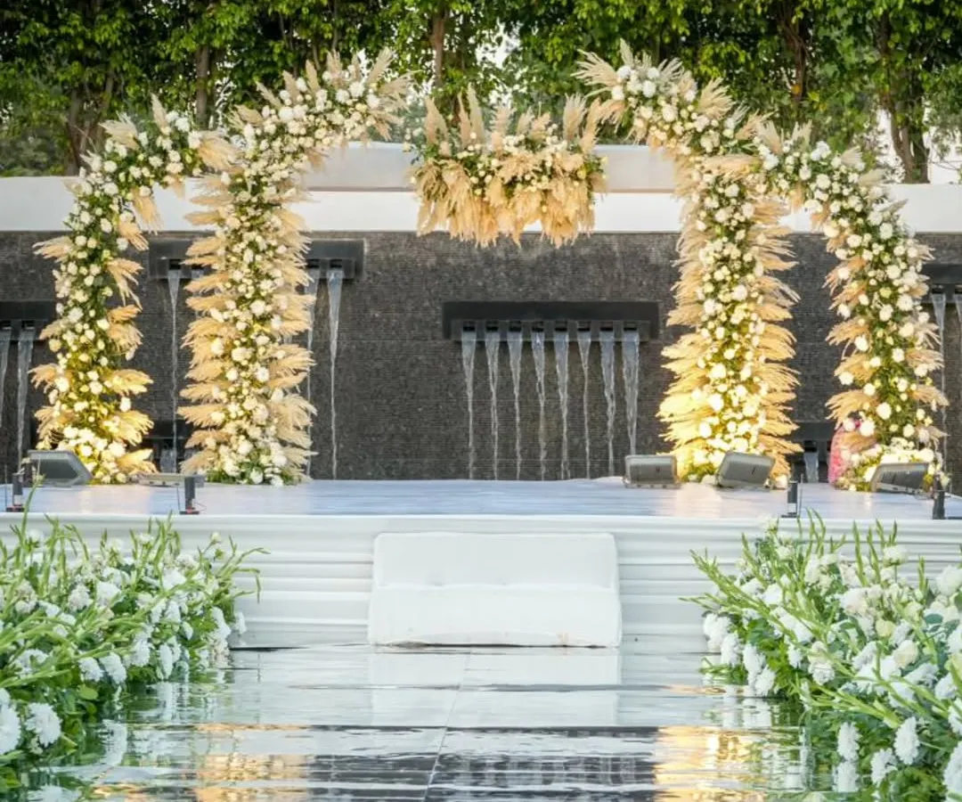 For a 25th anniversary, we created this ethereal sundowner celebration over water. The all-white floral arch against the cascading waterfall backdrop speaks of timeless elegance and enduring love, making for a truly exquisite milestone.