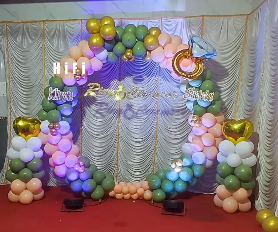 For your ring ceremony, I can create a beautiful and symbolic backdrop. This setup uses a circular balloon arch in olive green and peach, accented with a large diamond ring foil balloon and custom lettering for the couple's names, making the moment picture perfect.