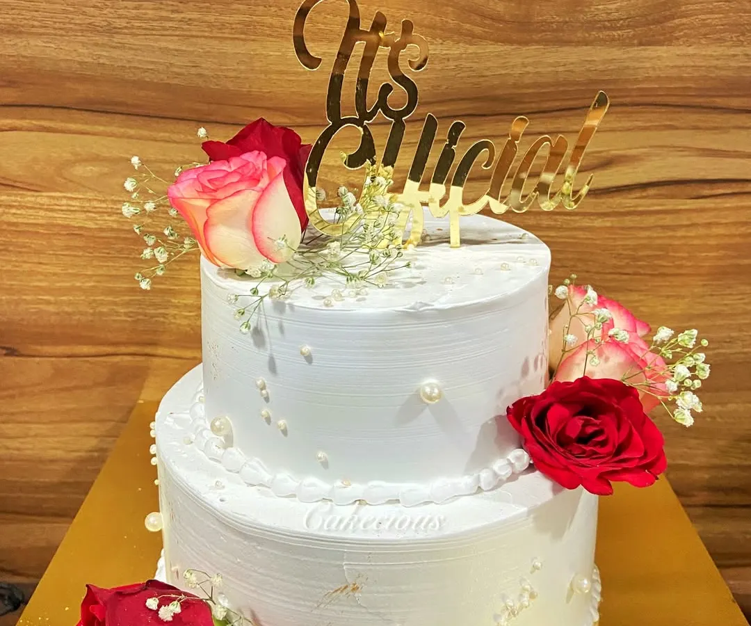 I believe every love story deserves a beautiful cake. This is a two-kilogram, two-tier Dutch Truffle engagement cake, decorated with fresh roses and baby's breath to mark the couple's special "It's Official!" moment.