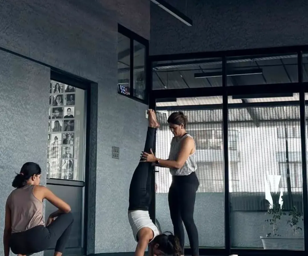 In my advanced workshops, we explore what the body is capable of with focus and safe guidance. Here, I'm assisting a student with her Pincha Mayurasana alignment. These sessions are about building the strength and confidence to safely go upside down.