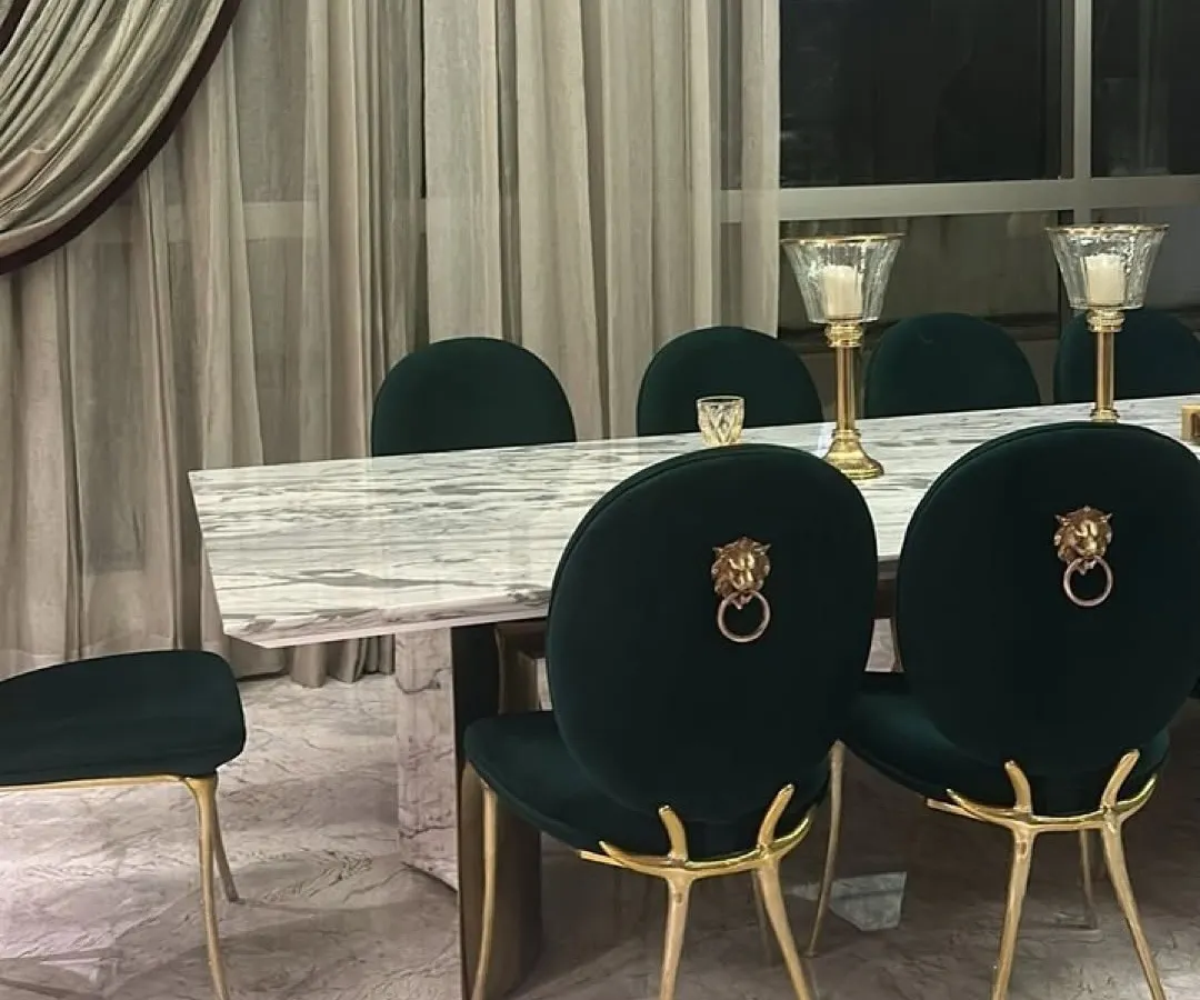 A statement in luxury dining. These custom emerald green velvet chairs feature bold lion head knockers and sculptural gold legs, paired with a substantial marble-topped table. This set was created to be the centerpiece of a grand dining space, reflecting our commitment to opulent and personalized design.