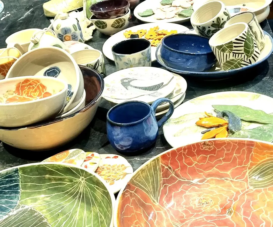 A glimpse of my stall at a pop up, filled with a variety of my handmade ceramics. You can see large floral platters, hand-painted mugs with geometric patterns, and an assortment of bowls, each with its own distinct character and glaze.