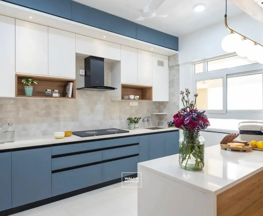 This modern modular kitchen features a striking dual-tone design with serene blue base cabinets and crisp white overhead storage. The quartz countertop island provides extra workspace and a casual dining spot, perfect for a busy family home.