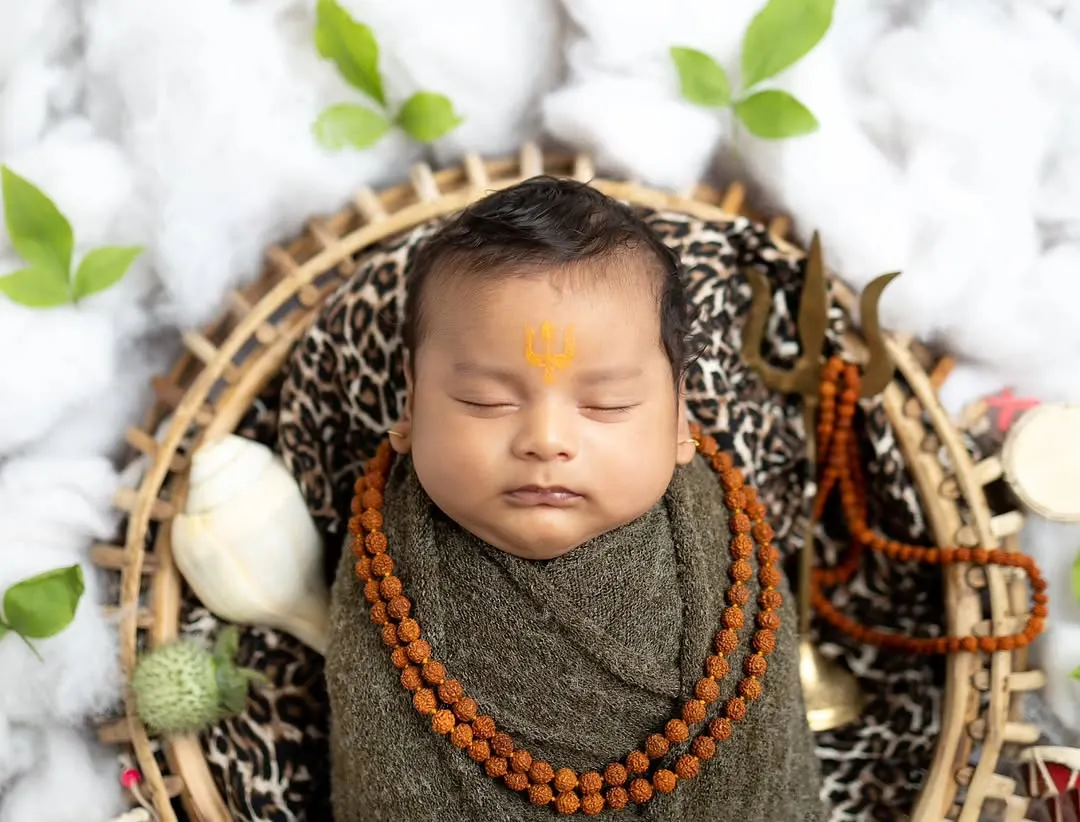 A 'Har Har Mahadev' themed shoot for this little one. I use soft wraps, a rudraksha mala, and iconic props like the trishul and damaru to create a divine and safe setting, perfect for capturing these blessed early days.