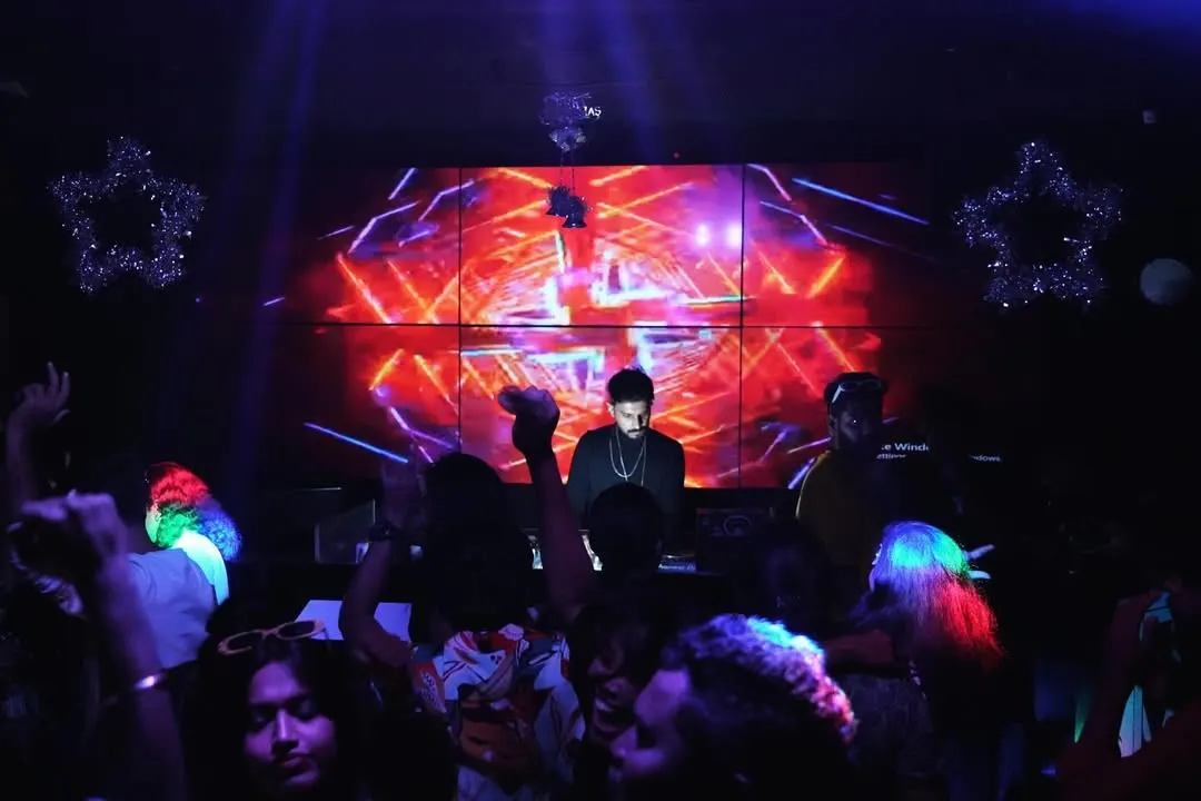 At the heart of my setup is the visual experience. Here I am at the console, surrounded by the crowd, with a massive LED wall displaying custom VJ graphics that sync perfectly with the EDM and bass house tracks.