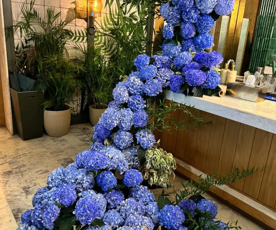 For this event, I designed a floral plunge pool using hundreds of blue hydrangeas. The goal was to create a breathtaking moment of drama and immersion, turning a simple corner into a sensational, cascading river of flowers.