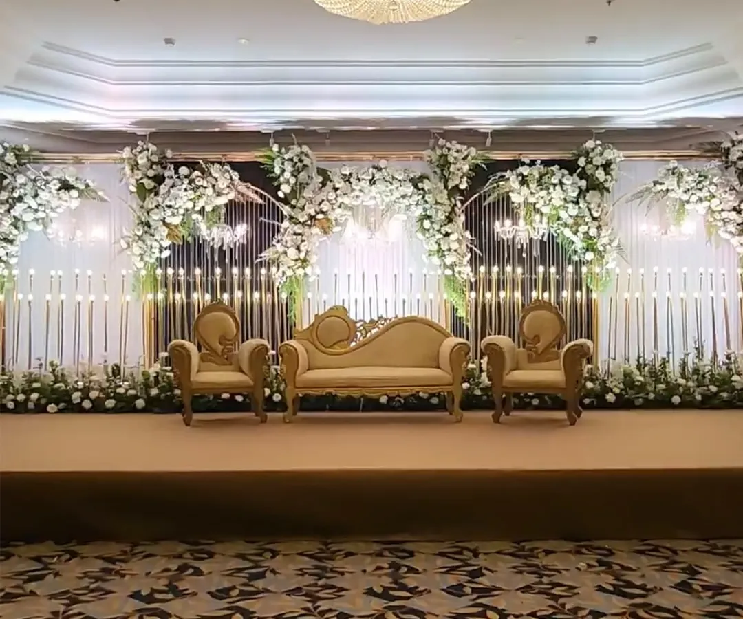 This stage design embodies pure elegance for a classic reception. We combined grand Victorian-style seating with a modern backdrop of cascading white florals and hundreds of warm, glowing candles to create a truly romantic focal point.