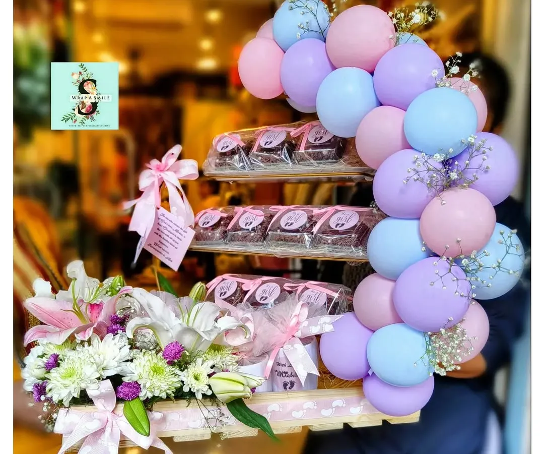We were so excited to create this special hamper to celebrate the arrival of twins for the Ambani-Piramal family. This arrangement features a beautiful balloon cluster in pastel pink, blue, and purple, paired with a fresh floral display of lilies and chrysanthemums. A tiered stand of delicious brownies adds a sweet touch to this grand welcome gift.