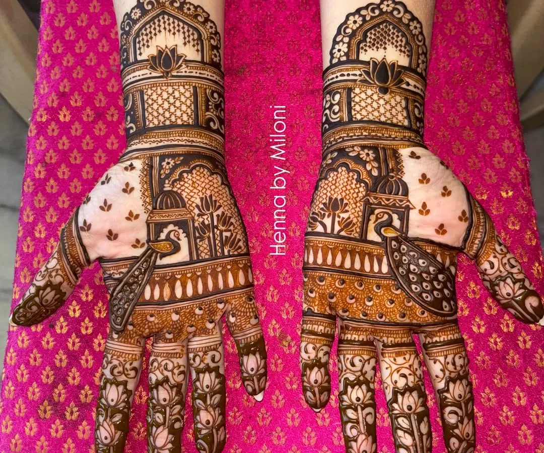 A classic Rajasthani bridal mehendi featuring intricate jharokha windows and peacock motifs. The design is symmetrical across both hands, creating a stunning, regal look for the modern bride.