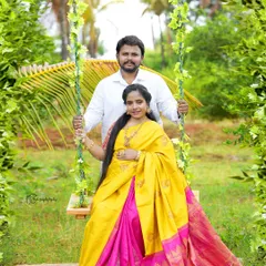 A vibrant outdoor portrait of a couple on our floral swing. The mother-to-be is wearing a bright yellow and pink silk saree that radiates joy.
