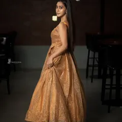 Elegance meets mood. This shot uses low-key lighting in an indoor setting to create a cinematic feel, highlighting the texture of the gown and the subject's quiet grace. It's a perfect example of a fashion-forward portrait.