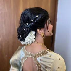 A detailed shot of the elegant hair bun, decorated with fresh white flowers and delicate hairpins. This hairstyle is a timeless choice for an engagement ceremony.