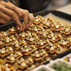 The final touch. Our chef carefully places a microgreen on a canapé, ensuring every bite is a perfect composition of flavor and beauty.