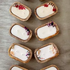 A closer view of my handpoured soy wax candles in carved wooden bowls. I adorn them with dried flowers and spices that complement the chosen fragrance, making each candle a unique piece of art.