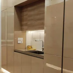 This view highlights the seamless integration of the sink and countertop with high-gloss, handleless cabinetry. The under-cabinet lighting provides excellent task illumination while adding a warm ambiance.