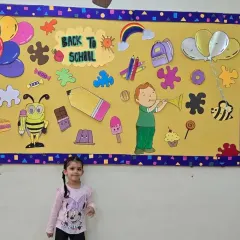 Two friends on their first day, standing in front of our colorful 'Back to School' bulletin board.