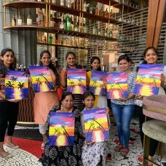 A happy group from Trio Technologies shows off their sunset paintings at RCB Cafe in Bangalore. This is the classic sip and paint experience: good vibes, guided art, and a masterpiece to take home.