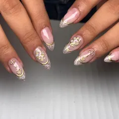 This elegant nail set is perfect for a bride or any special occasion. It combines a glittery French tip with delicate gold swirls and pearl embellishments for a sophisticated and glamorous finish.