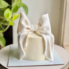 It's giving cake couture. 🤍 This minimal buttercream cake is finished with a dramatic, hand-sculpted fondant bow that looks just like satin. It’s a statement of pure elegance and artistry.