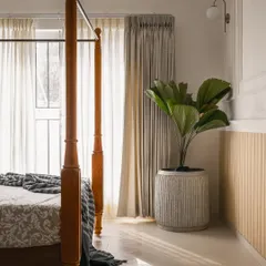 Natural light streams into this bedroom, highlighting the textures of the space. We use sheer curtains to soften the light and incorporate indoor plants, like this fiddle leaf fig, to enhance the connection to the outdoors.