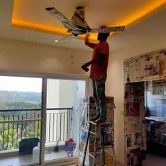 Details make the difference. Here, one of my painters is carefully working on the ceiling, ensuring the area around the fan and light fixtures is painted with precision. We cover everything to promise a neat job.