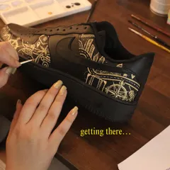 One brushstroke at a time. Here's a look at the process of painting a detailed city skyline and travel-themed icons onto a pair of black Nike Air Force 1s.