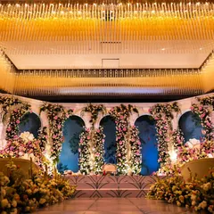 This stage design uses classic architectural elements like floral-draped arches to create a sense of timeless elegance. The soft lighting and pastel color palette make for a romantic and sophisticated reception setting.