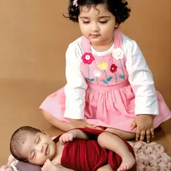 Welcoming a new member to the family is a special milestone. This sibling photoshoot captures the gentle curiosity and love between an older sister and her new baby brother.